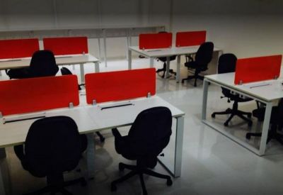 Coworking space featuring white desks with vibrant red privacy dividers and black swivel chairs.