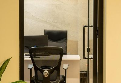 A private office suite seen through a glass door with a mesh chair and wooden floors.