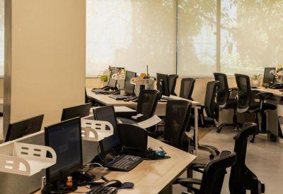 Modern open-plan workspace with multiple rows of desks and ergonomic mesh chairs.