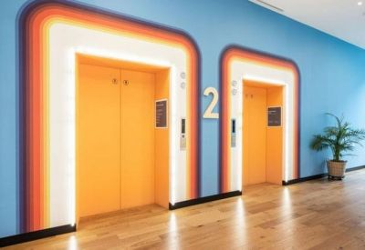 Colorful elevator lobby with vibrant orange doors and a retro rainbow wall design.