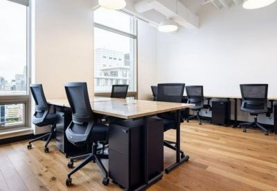 Bright office space featuring wooden floors and individual workstations with ergonomic chairs.
