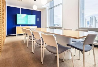 Professional meeting room with a large white table, blue chairs, and a wall-mounted screen.