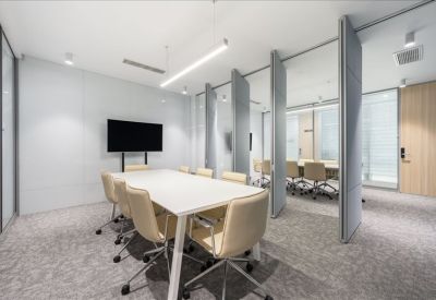 Large meeting room featuring a white conference table, cream chairs, and acoustic privacy screens.