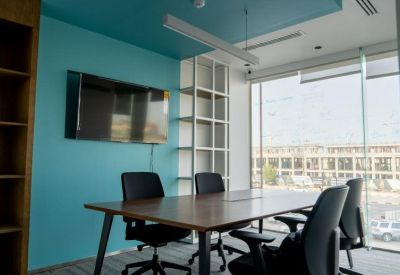 Meeting room with a teal feature wall, large windows, and a wooden conference table.