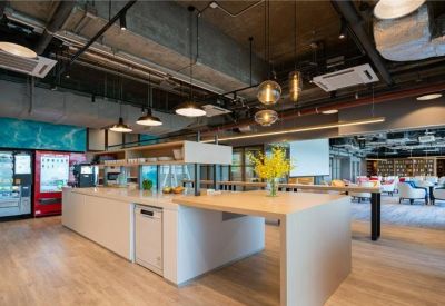 Modern communal kitchen and breakout area with a central island and pendant lighting.