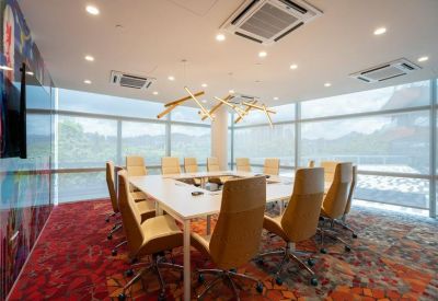 Sunlit boardroom with a large white table, tan leather chairs, and floor-to-ceiling windows.