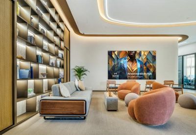 Bright lounge area with orange armchairs, a large digital display, and extensive bookshelves.