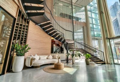 Grand lobby entrance with a curved sofa, indoor plants, and a striking spiral staircase.