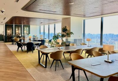 Spacious coworking area with wooden ceilings and large windows overlooking the city.