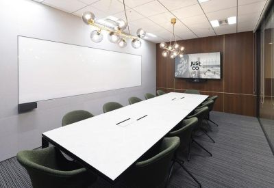 Sleek meeting room featuring a long white table, green chairs, and a large whiteboard.