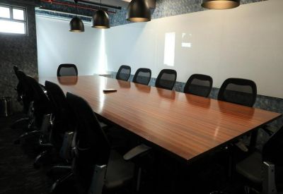 Spacious boardroom featuring a polished wooden table and black mesh executive chairs.