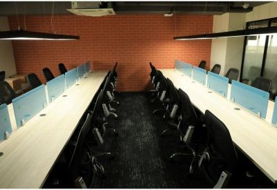 Symmetrical view of a modern coworking area with long white desks and dark carpet.