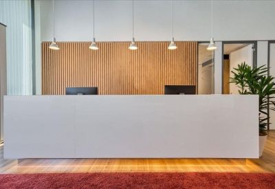 Clean white reception desk with wood paneling and decorative hanging lights.