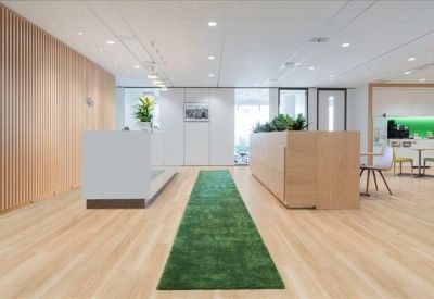 Minimalist reception area featuring a white desk, wooden accents, and a green runner rug.