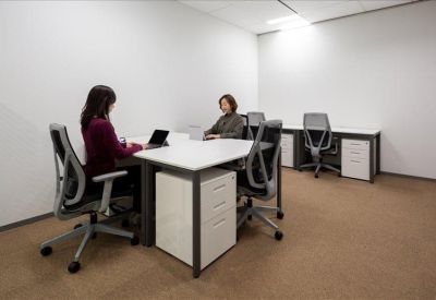 Private two-person office suite with white desks and grey ergonomic chairs.