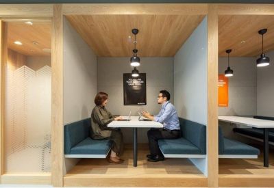 Semi-private meeting booths with blue cushioned seating and light wood paneling.
