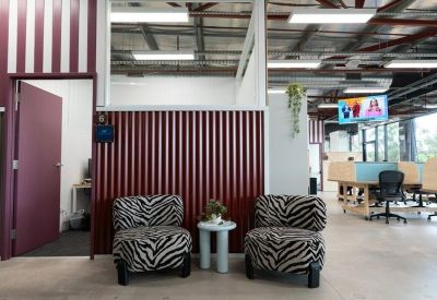 Breakout area with zebra-print armchairs, a small side table, and a wall-mounted TV.