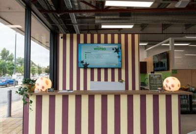 Reception desk with maroon and cream stripes featuring a digital display and warm lamps.