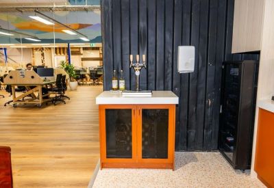 Hospitality station featuring a beer tap and wine fridge against a dark wood wall.
