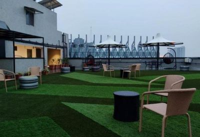 Expansive rooftop terrace featuring artificial turf, patio seating, and views of the surrounding city skyline.
