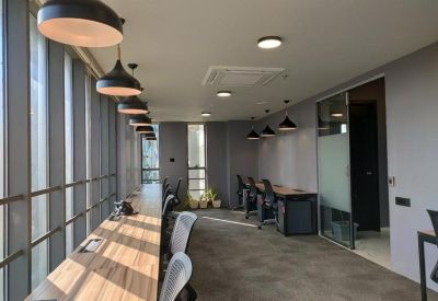 Contemporary coworking area with wooden desks along a large window wall and modern pendant lighting.