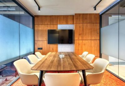 Professional board room with a long wood-grain table, white bucket chairs, and a large flat-screen display.