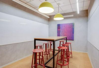 Small meeting room with a high table, red stools, and whiteboards.
