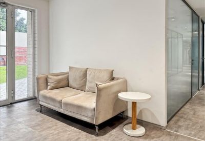 Minimalist communal lounge area featuring a beige velvet sofa and a small round side table.