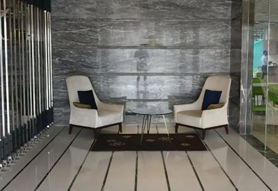Polished marble lobby with two elegant armchairs and orb pendant lights.