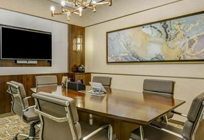 Upscale boardroom with a large wooden table, leather chairs, and elegant gold ceiling trim.