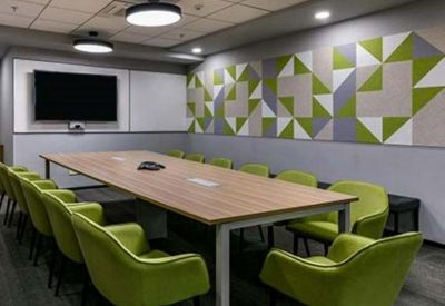 Modern meeting room featuring lime green chairs and a geometric pattern accent wall.