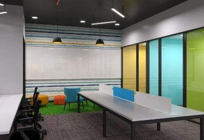 Modern office interior with long white desks, blue privacy screens, and a green accent floor.