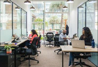 Bright glass-partitioned office area with multiple workstations and natural light.