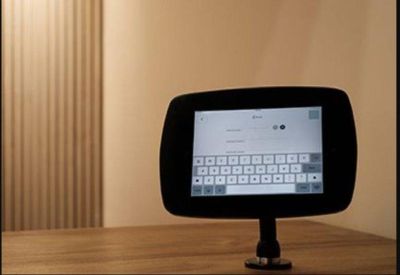 Tablet-style digital room booking display on a wooden desk.