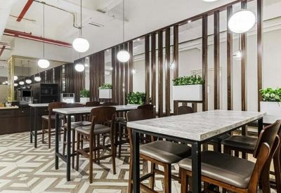 Communal dining area with high tables, wooden chairs, and geometric floor tiles.