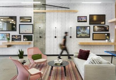 Lounge area with pink armchairs, a white sofa, and a gallery wall on white brick.
