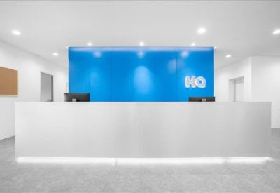 Modern white reception desk set against a bright blue feature wall with HQ branding.
