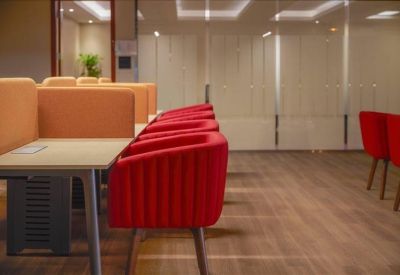 Coworking space featuring partitioned desks and vibrant red armchairs.