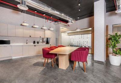 Modern communal kitchen and breakout area with vibrant red armchairs and wood accents.