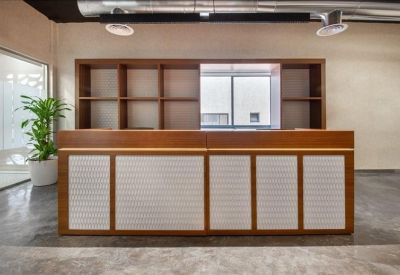 Professional wooden reception desk with white textured front panels and a potted plant.