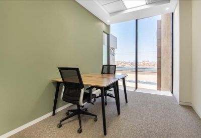 Private two-person office with a green accent wall and floor-to-ceiling windows.