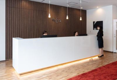 Minimalist white reception desk with warm under-lighting and wood-paneled feature wall.