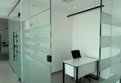 Glass-walled corridor view showing a private office suite with frosted privacy bands.