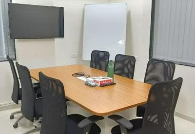 Six-person meeting room with wooden table and wall-mounted screen.