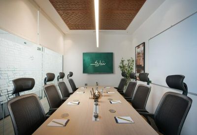 Contemporary boardroom with a long light wood table, black mesh chairs, and a decorative wooden ceiling.