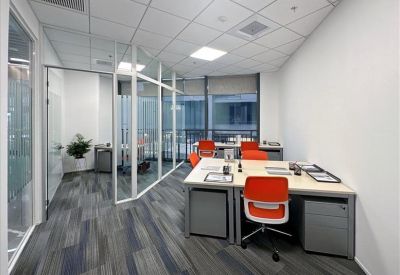 Spacious corner office with natural light, orange chairs, and glass partitions.