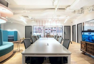 Open plan office space with a large white shared desk and soft lounge seating.