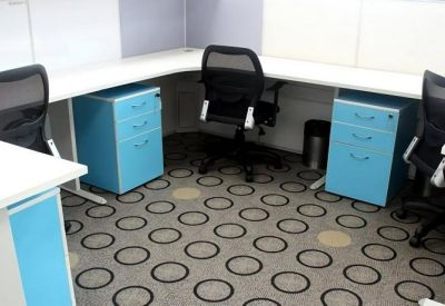 Functional open-plan workspace with white L-shaped desks and bright blue mobile filing cabinets.