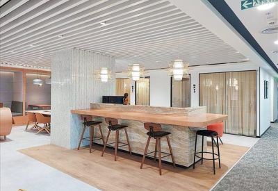 Bright breakout area with a stone-finish bar counter and high stools under a slatted ceiling.