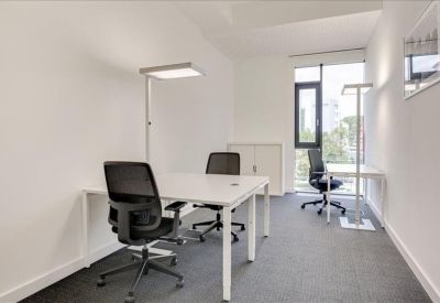 Bright private office featuring white desks, ergonomic black chairs, and floor-to-ceiling windows.